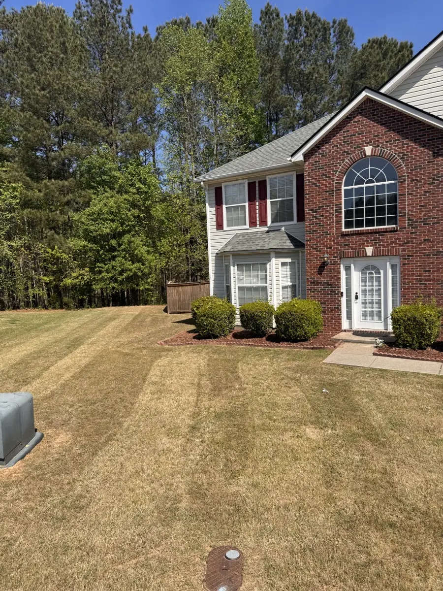 Front and side lawn with mowing stripes next to a two-story brick and siding house